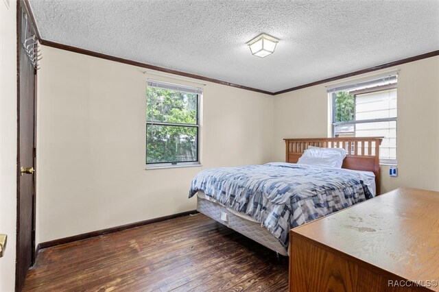 bedroom with ornamental molding, a textured ceiling, multiple windows, and dark wood-type flooring