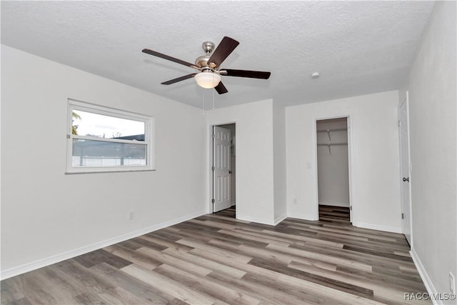 9019 E Gulf To Lake Hwy, Inverness, FL 34450 - unfurnished bedroom featuring wood finished floors, a textured ceiling, a ceiling fan, a closet, and a spacious closet