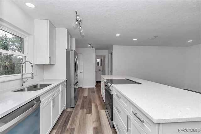 9019 E Gulf To Lake Hwy, Inverness, FL 34450 - kitchen with appliances with stainless steel finishes, a textured ceiling, white cabinetry, dark wood finished floors, and a kitchen island