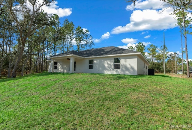 rear view of house featuring a yard and ceiling fan