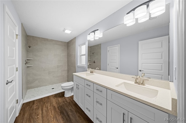 bathroom with toilet, wood-type flooring, and tiled shower