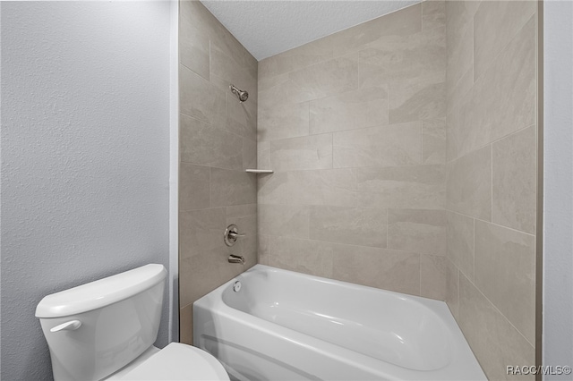 bathroom with a textured ceiling, tiled shower / bath combo, and toilet