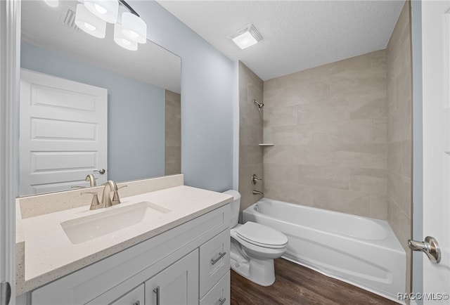 full bathroom featuring vanity, tiled shower / bath, toilet, a textured ceiling, and wood-type flooring