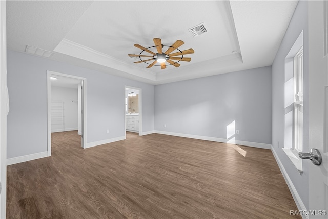 spare room featuring a raised ceiling, ceiling fan, plenty of natural light, and dark wood-type flooring