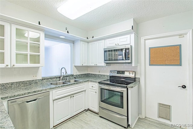 6176 W Pinedale Cir, Crystal River, FL 34429 - kitchen featuring stainless steel appliances, light wood-style flooring, white cabinetry, backsplash, and a textured ceiling