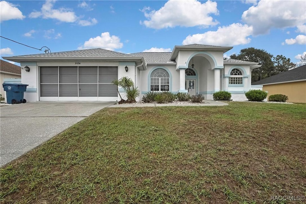 view of front of property featuring driveway, a front lawn, an attached garage, and stucco siding