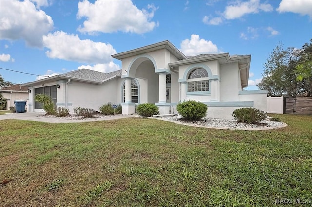 mediterranean / spanish house with a shingled roof, concrete driveway, an attached garage, a front lawn, and stucco siding