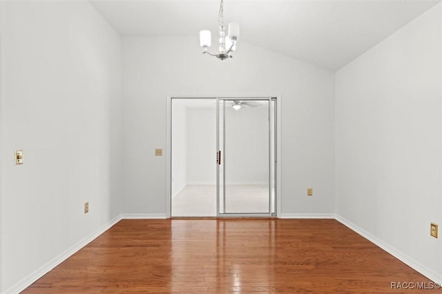 spare room featuring hardwood / wood-style flooring, vaulted ceiling, and an inviting chandelier