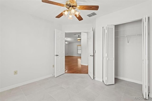 unfurnished bedroom with light tile patterned floors, a closet, and ceiling fan