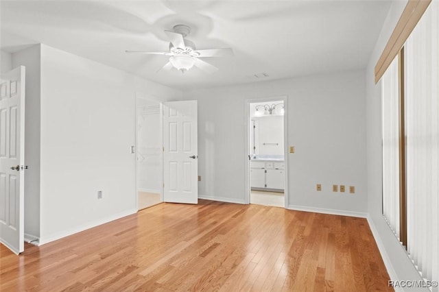 unfurnished bedroom featuring hardwood / wood-style floors, a spacious closet, ceiling fan, ensuite bath, and a closet