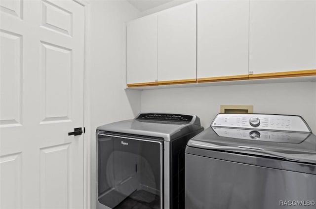 clothes washing area featuring cabinets and separate washer and dryer