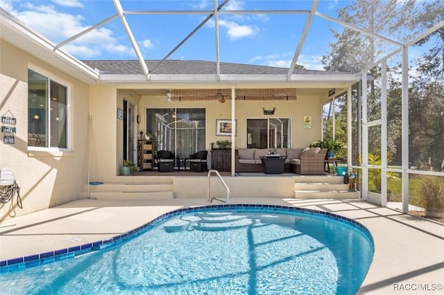 outdoor pool with a ceiling fan, glass enclosure, a patio, and an outdoor living space