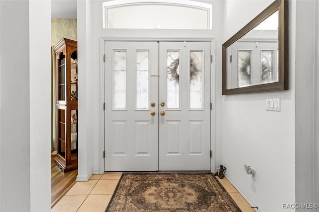 foyer entrance with light tile patterned floors and baseboards