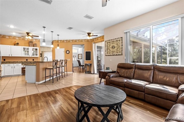 living area with visible vents, ceiling fan, and light tile patterned flooring