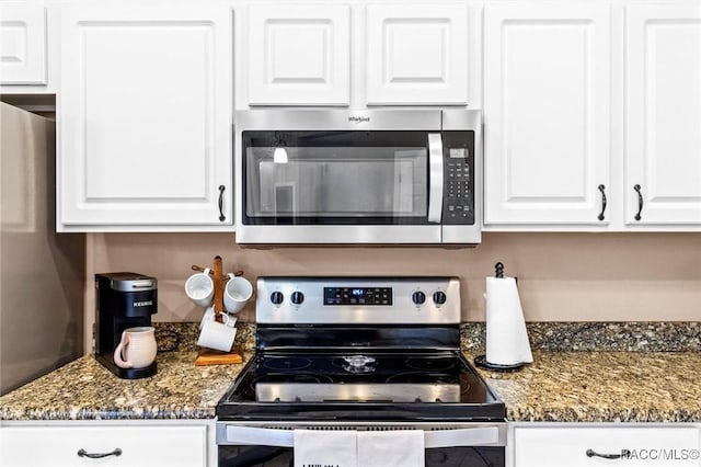 kitchen with stainless steel appliances, dark stone countertops, and white cabinets