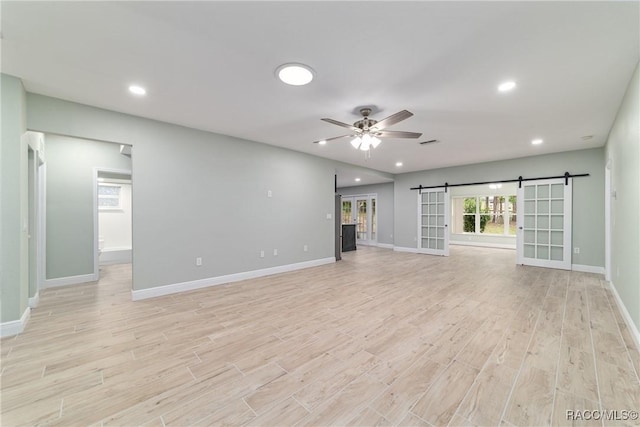 19028 SW 101st Pl, Dunnellon, FL 34432 - unfurnished living room featuring a barn door, light wood-type flooring, baseboards, ceiling fan, and recessed lighting