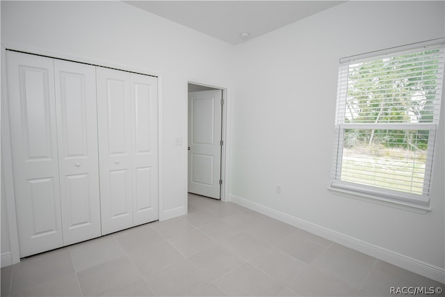 unfurnished bedroom featuring multiple windows, a closet, and light tile patterned flooring