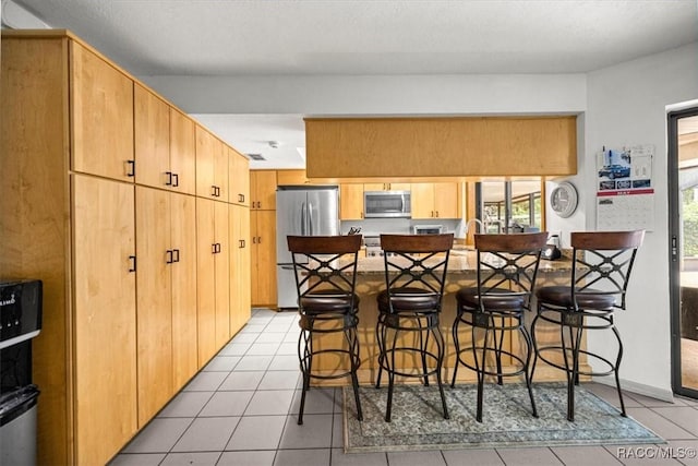 4357 N Indianhead Rd, Hernando, FL 34442 - kitchen with stainless steel appliances, a peninsula, light tile patterned flooring, and a kitchen breakfast bar