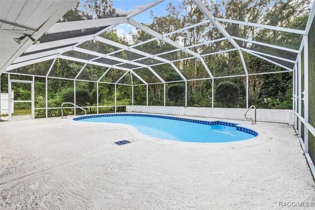 view of pool featuring glass enclosure and a patio