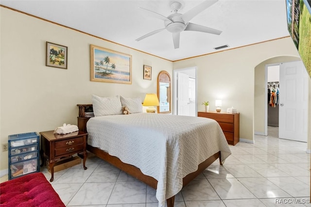 bedroom featuring ceiling fan, crown molding, a spacious closet, a closet, and light tile patterned flooring