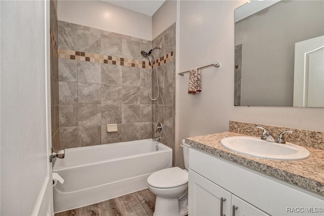 full bathroom featuring hardwood / wood-style flooring, tiled shower / bath, vanity, and toilet