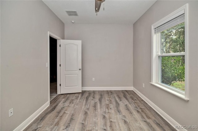 unfurnished room featuring ceiling fan, a healthy amount of sunlight, and light wood-type flooring