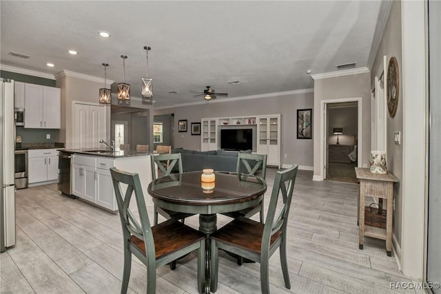 dining space with ceiling fan, ornamental molding, and sink