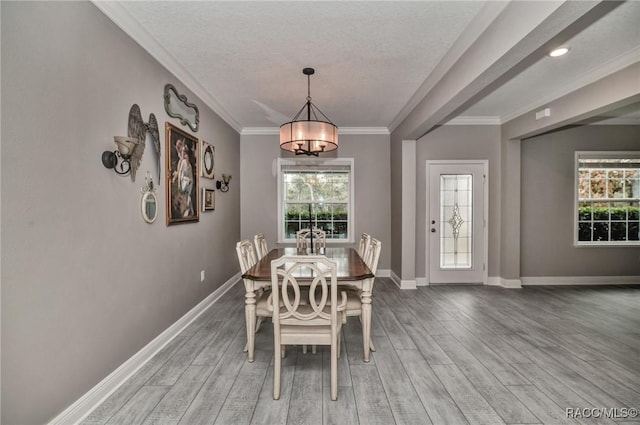 dining space featuring crown molding, hardwood / wood-style floors, a notable chandelier, and a textured ceiling