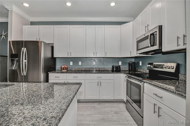 kitchen featuring dark stone countertops, white cabinets, and appliances with stainless steel finishes