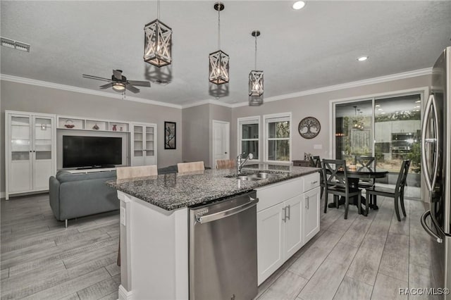 kitchen featuring sink, stainless steel appliances, an island with sink, white cabinets, and dark stone counters