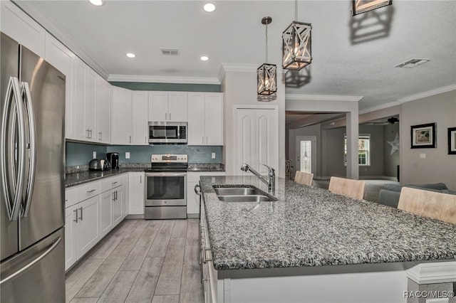 kitchen with stainless steel appliances, sink, pendant lighting, and white cabinets