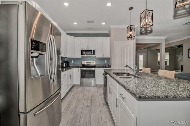 kitchen with stainless steel appliances, sink, a center island with sink, and white cabinets