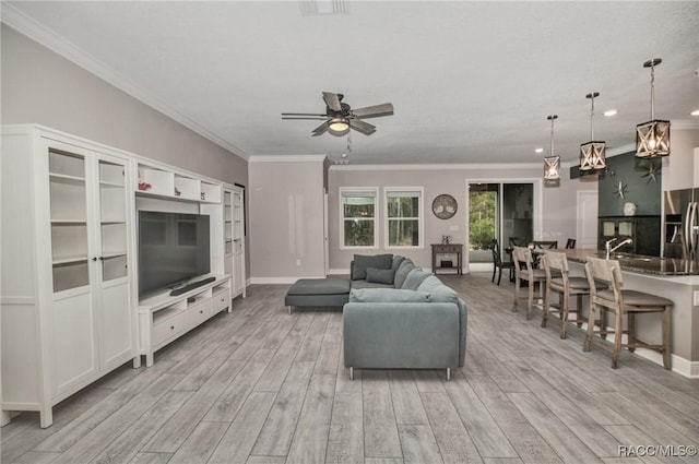 living room featuring sink, crown molding, light hardwood / wood-style floors, and ceiling fan