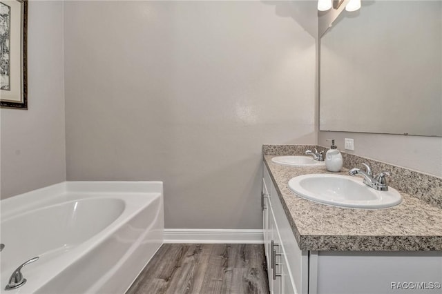 bathroom featuring wood-type flooring, a bath, and vanity