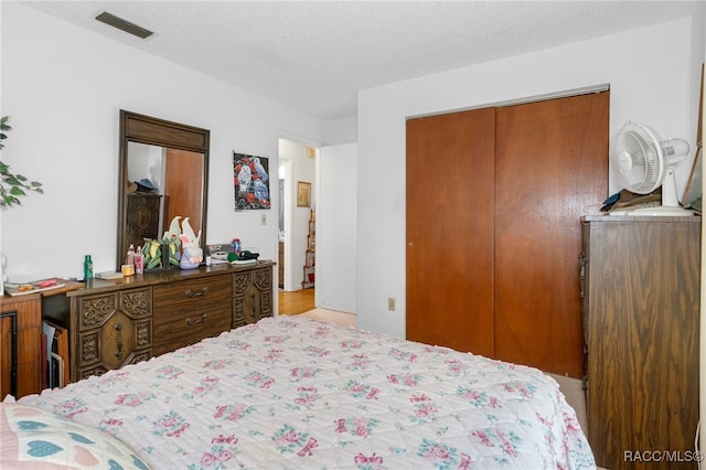 bedroom with a textured ceiling, light hardwood / wood-style flooring, and a closet