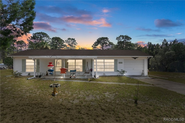 ranch-style home with stucco siding, a porch, a lawn, an attached garage, and driveway