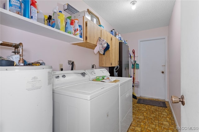 washroom with washer and dryer, a textured ceiling, gas water heater, and cabinets