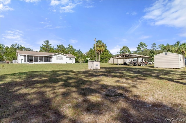 view of yard featuring a storage unit, a carport, and a sunroom