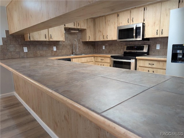 9781 E Goldfinch Ln, Inverness, FL 34450 - kitchen featuring appliances with stainless steel finishes, light brown cabinetry, backsplash, dark wood finished floors, and a sink