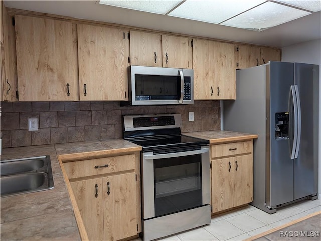 9781 E Goldfinch Ln, Inverness, FL 34450 - kitchen with stainless steel appliances, tasteful backsplash, light brown cabinetry, and light tile patterned floors