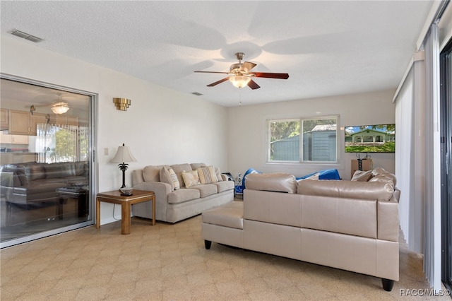 carpeted living room featuring ceiling fan and a textured ceiling