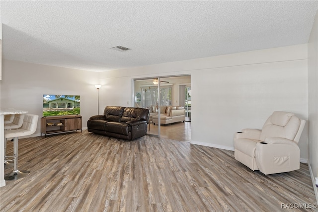 living room with ceiling fan, hardwood / wood-style floors, and a textured ceiling