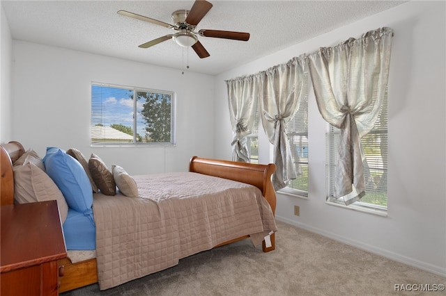 bedroom with multiple windows, ceiling fan, light colored carpet, and a textured ceiling