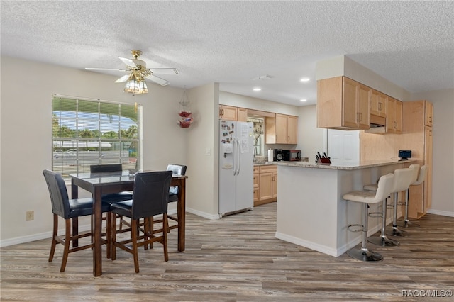 kitchen with light hardwood / wood-style flooring, white refrigerator with ice dispenser, and light brown cabinets