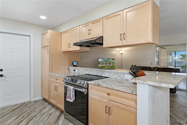 kitchen featuring light brown cabinets, stainless steel range with electric cooktop, a kitchen breakfast bar, light hardwood / wood-style flooring, and kitchen peninsula