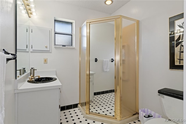 bathroom featuring a textured ceiling, vanity, toilet, and a shower with shower door