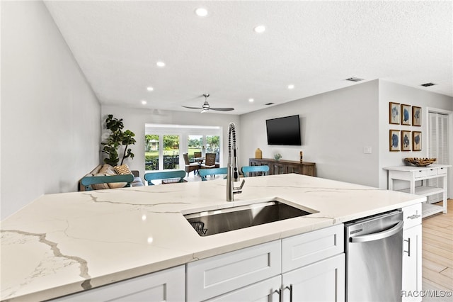 kitchen with dishwasher, white cabinets, sink, ceiling fan, and light wood-type flooring