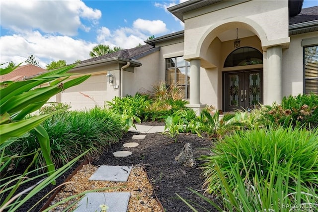 view of exterior entry featuring a garage and french doors