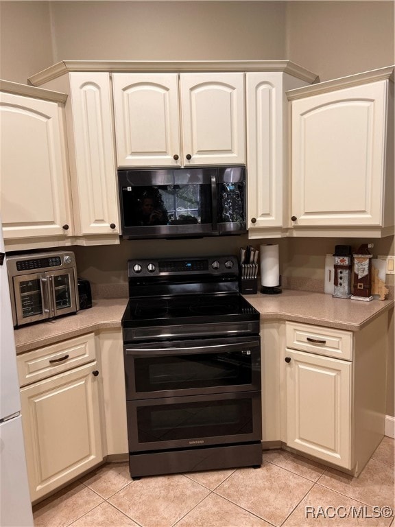 kitchen featuring white cabinets, light tile patterned floors, and black electric range