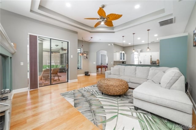 living room featuring a raised ceiling, ceiling fan, and hardwood / wood-style flooring